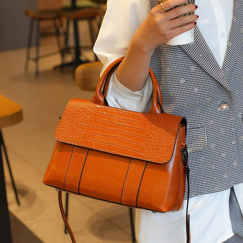 Person holding an orange handbag in a blurred indoor setting