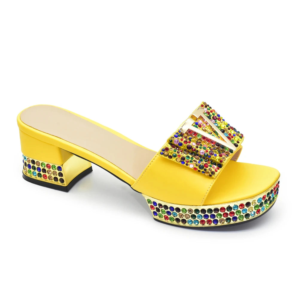 Yellow sandal with colorful rhinestone embellishments on a white background