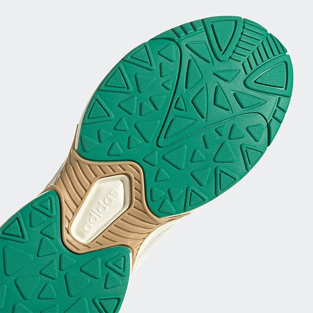 Close-up of a green and beige shoe sole with Adidas logo on a light gray background
