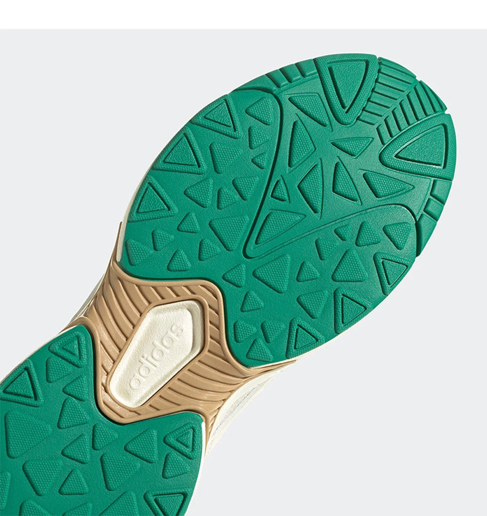 Close-up of a green and beige shoe sole with Adidas logo on a light gray background