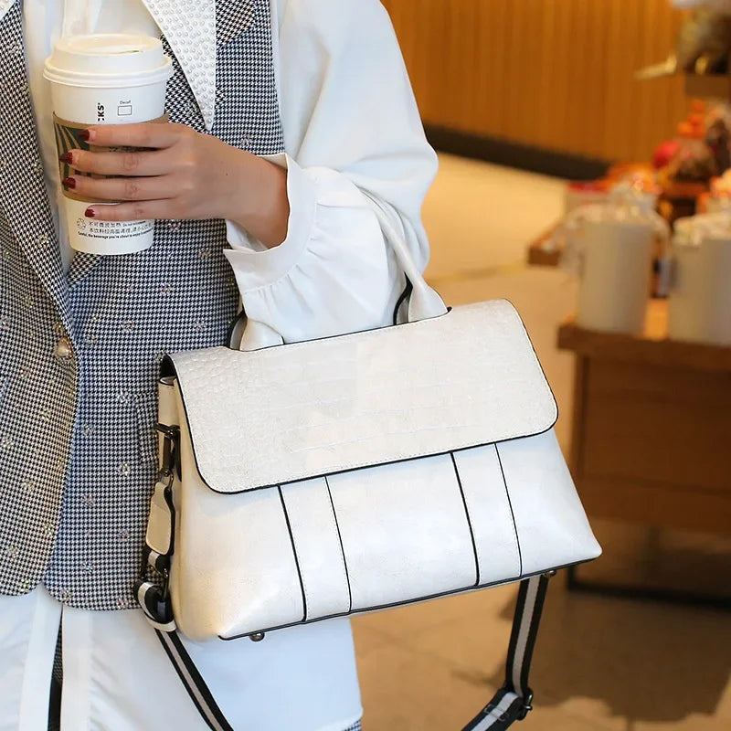 Person holding a white handbag and a coffee cup in an indoor setting
