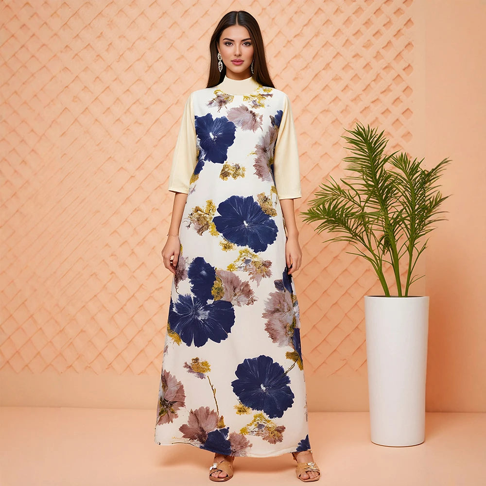 Woman wearing a floral dress standing next to a plant against a patterned wall.