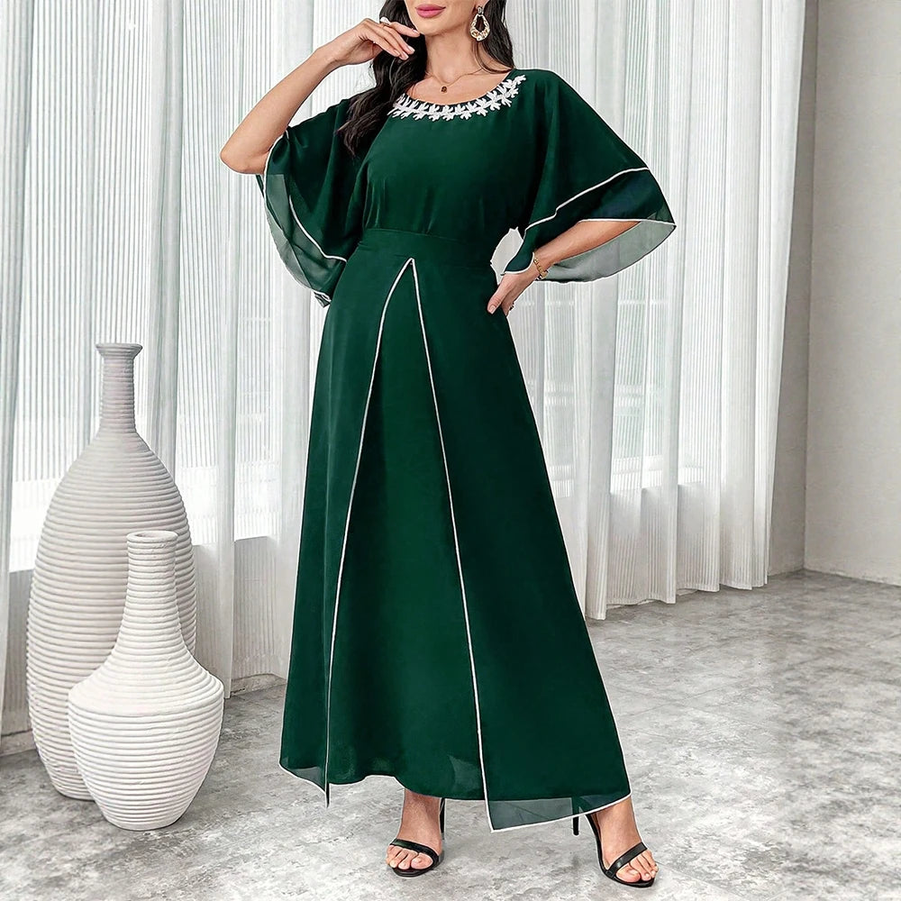 Woman wearing a green dress with white trim in a room with white vases.