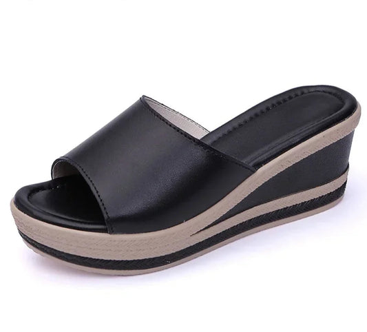 Black wedge sandal with beige sole on a white background.