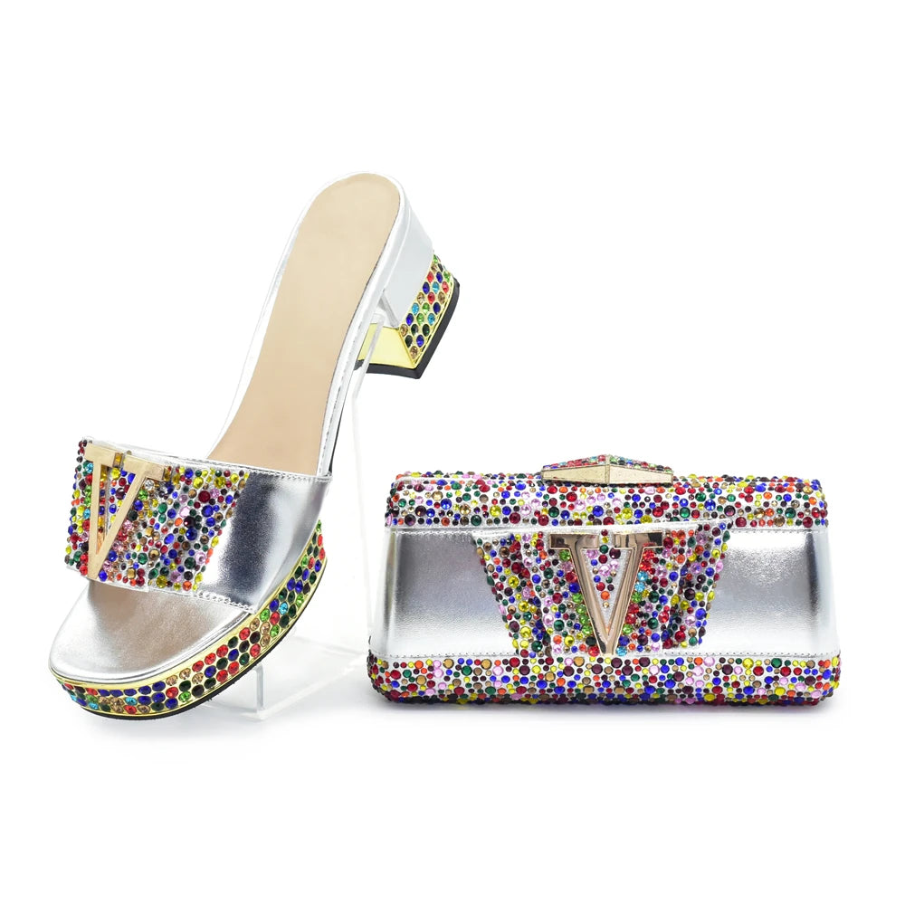 Silver high-heeled shoe with colorful embellishments and matching clutch bag on a white background