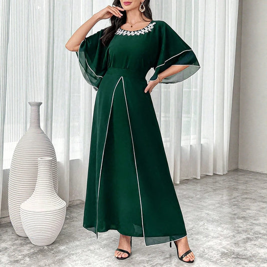 Woman wearing a green dress with white trim in a room with white vases.