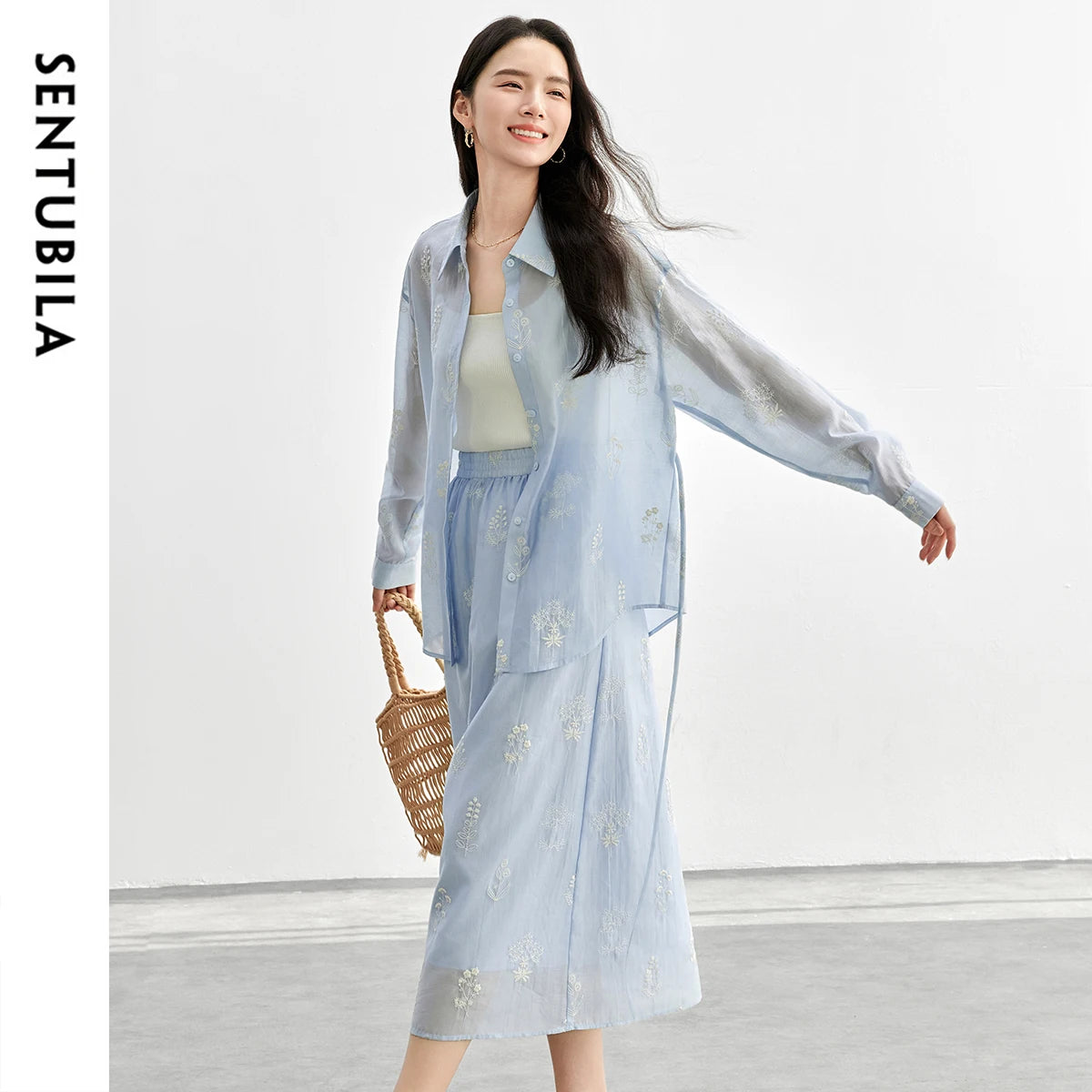 Woman wearing a light blue outfit with a white background, featuring the brand 'SENTUBILA'.