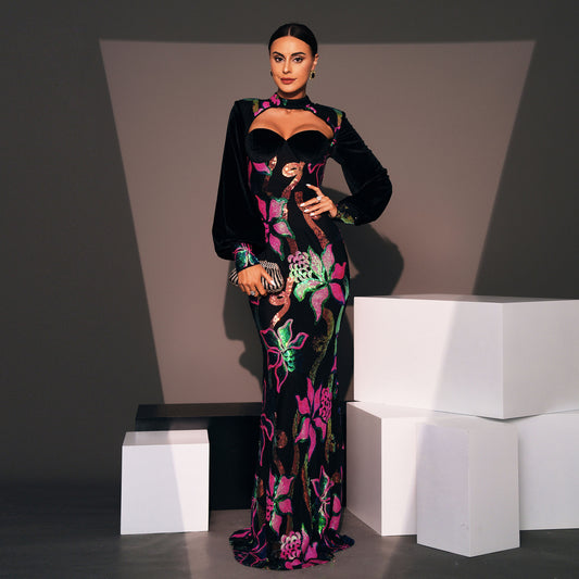 Woman in a floral evening gown standing against a gray background